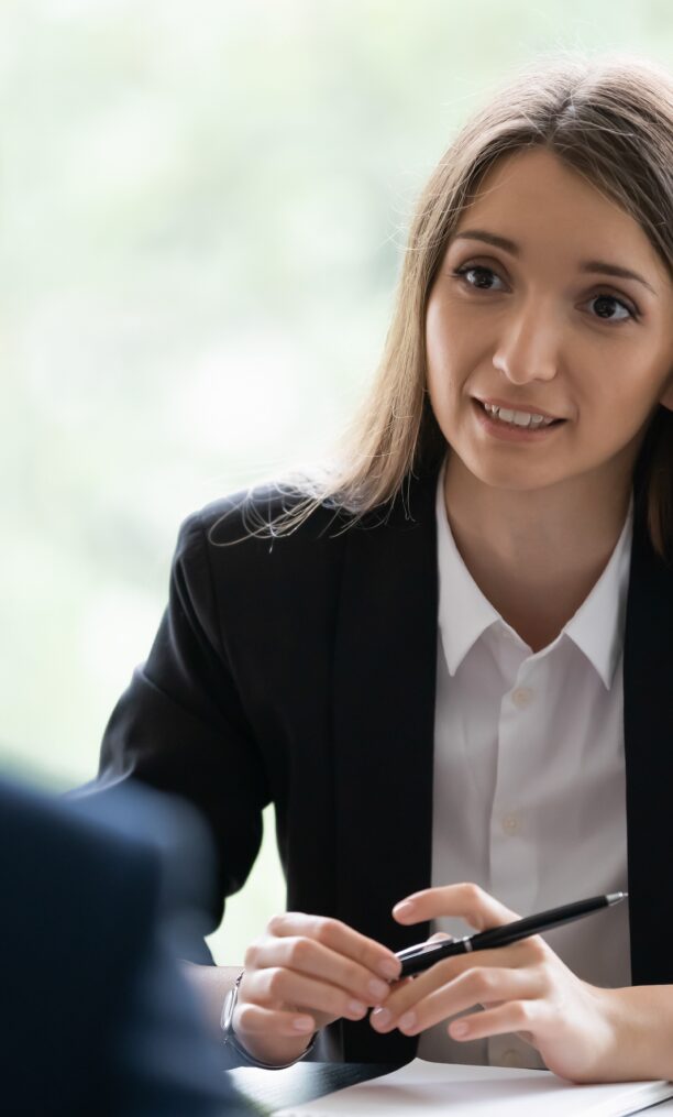 A woman in a business suit engages in conversation with a man in a professional setting.